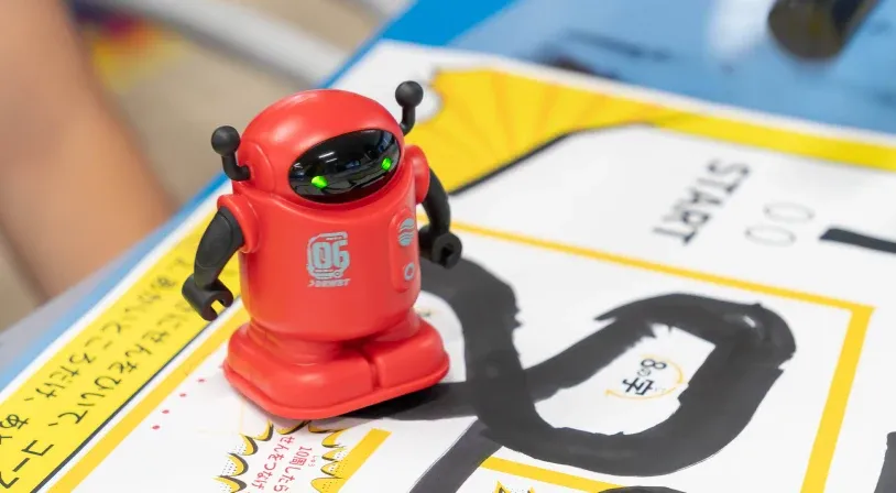 黒いペンで描いたコースをなぞって走る、赤いライントレースロボットのおもちゃ