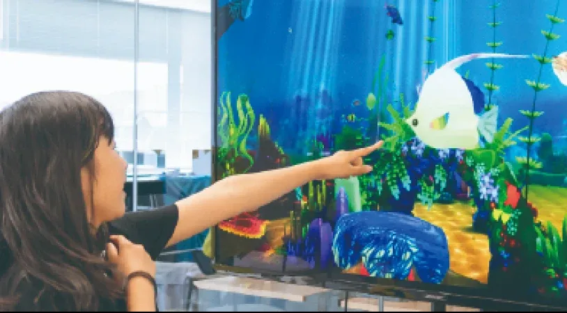 大画面のデジタル水族館に映る魚を指差す子ども