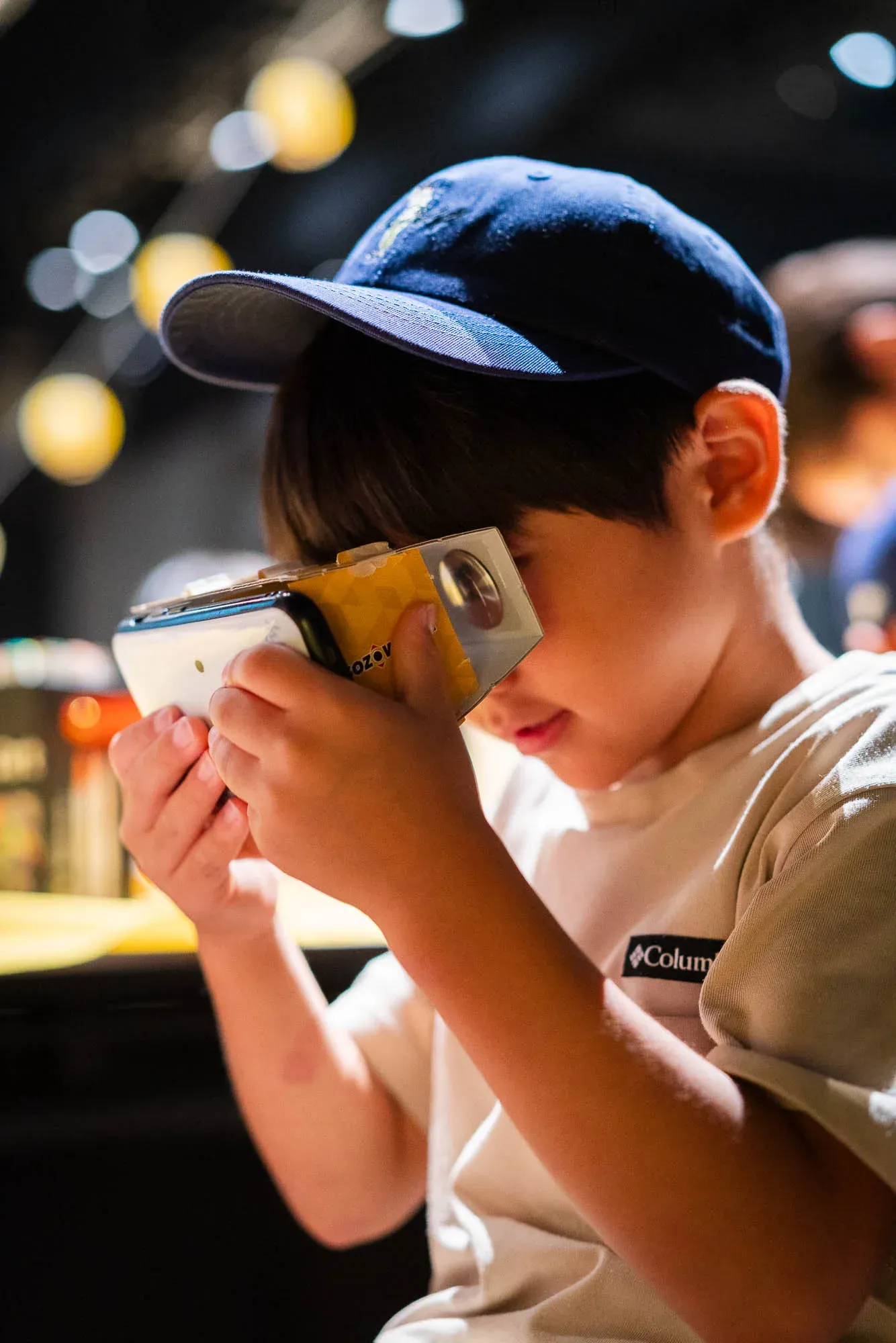 自分で組み立てたVRゴーグルにスマートフォンをセットしてのぞき込む子ども