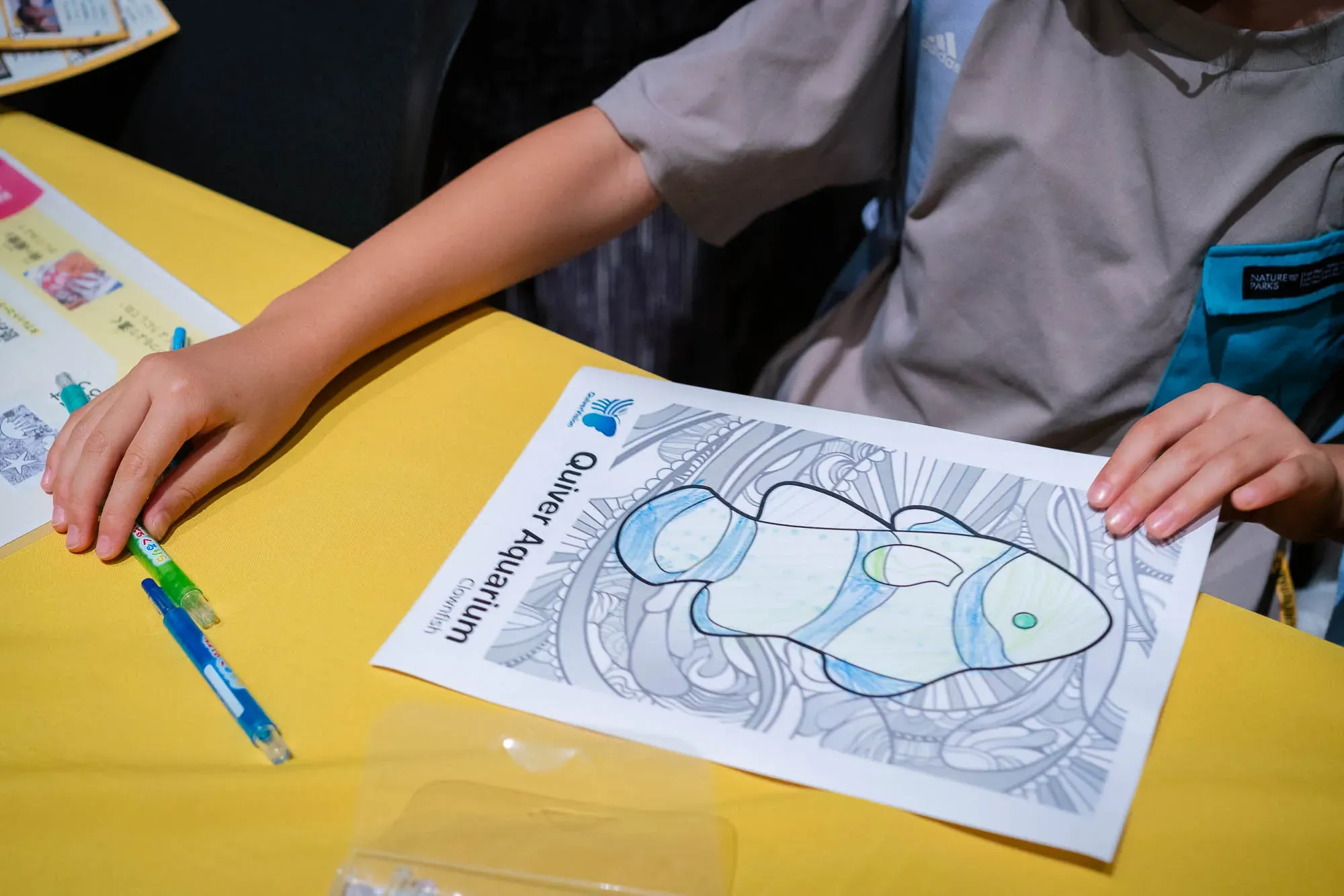 デジタル水族館の体験で、魚の塗り絵に色を塗る子どもの手元