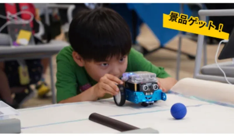 タブレットで動かすロボットを的に向けて構える子ども