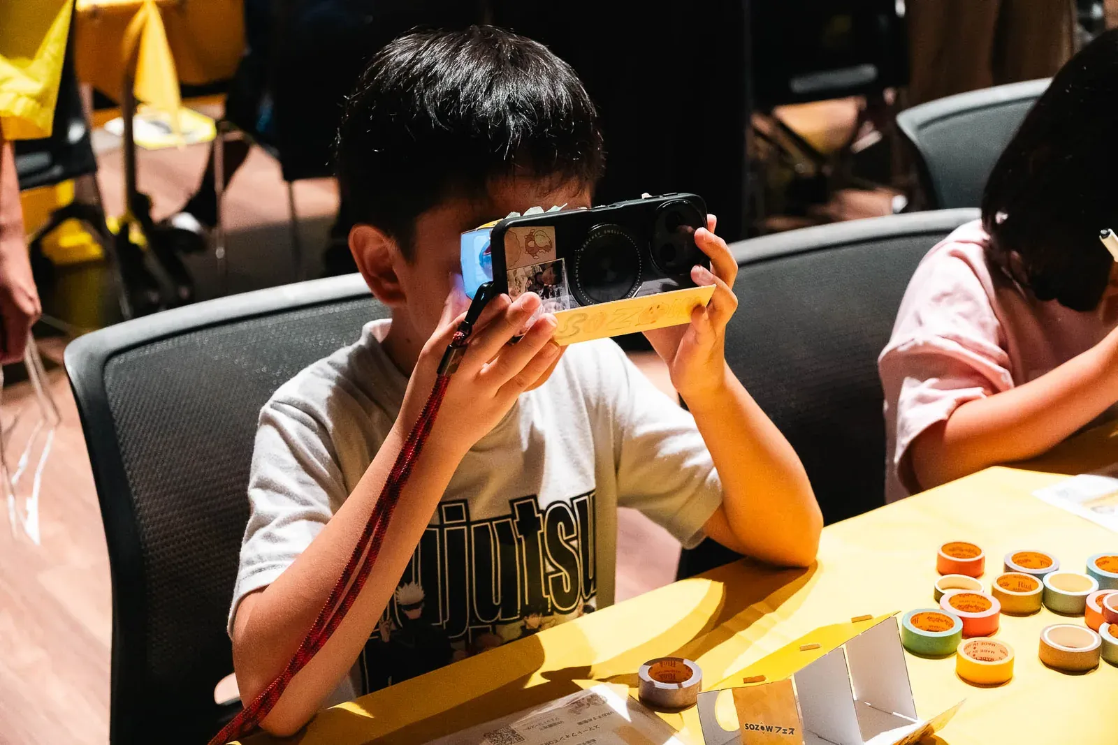 手作りしたVRゴーグルにスマートフォンをセットしてのぞき込む男の子