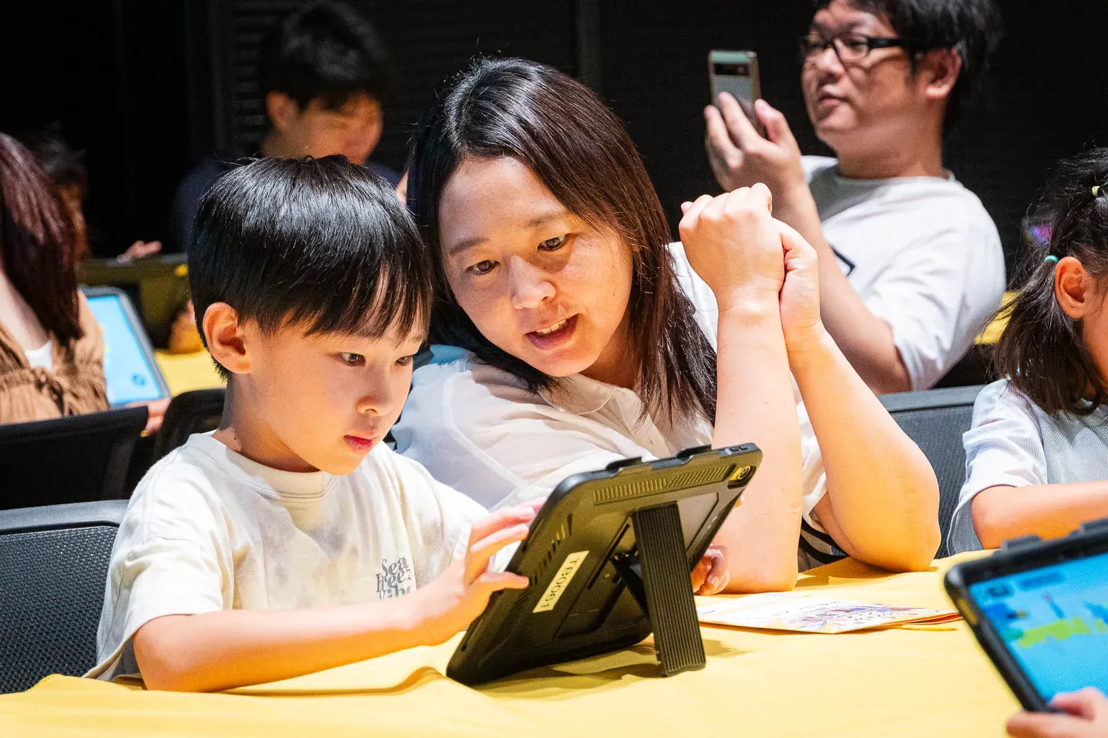 保護者と一緒にタブレットを操作しながら体験に取り組む男の子